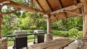 An outdoor patio with a wooden table and two grills. - MainStay Suites Columbus near Fort Benning (Columbus)