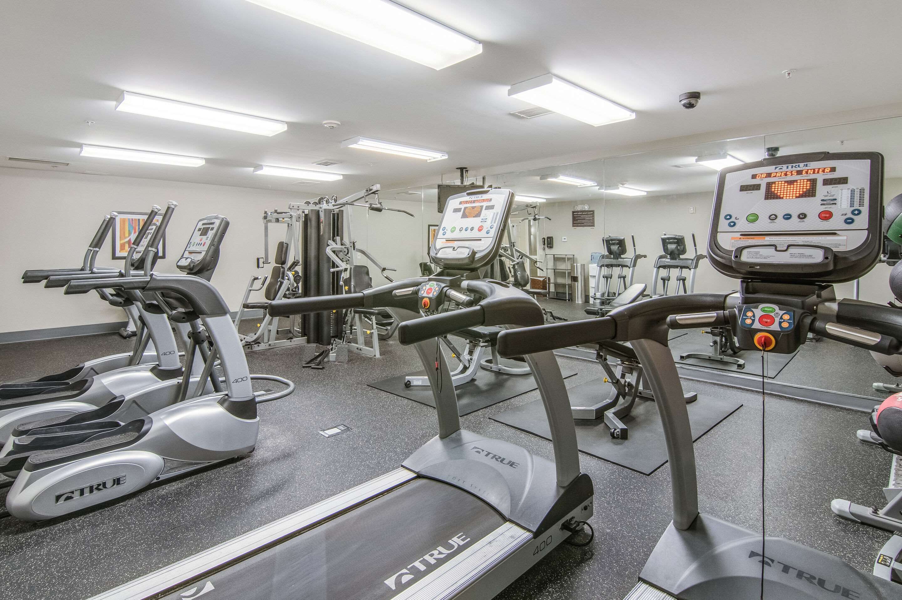 Un gimnasio con cintas de correr, elípticas y equipo de pesas.