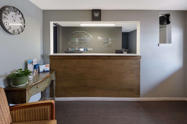 A reception area with a clock, a reception desk, and a sign for Suburban Extended Stay Hotel and Rodeway Inn. - Suburban Studios Brazil (Brazil)