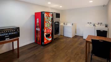 Une pièce équipée d’un distributeur automatique, d’une machine à laver et d’un four à micro-ondes.