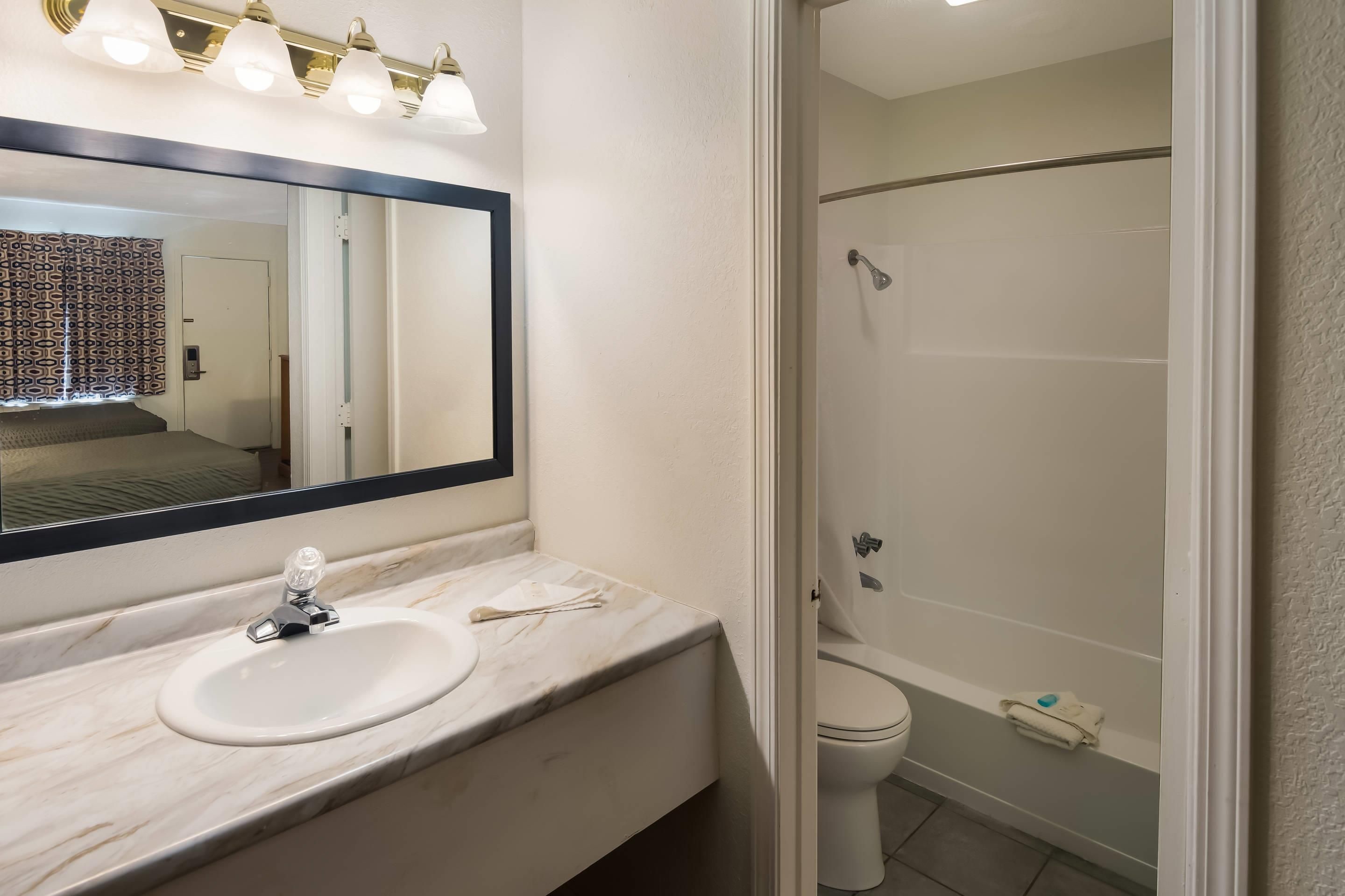 A bathroom with a sink, mirror, and shower.