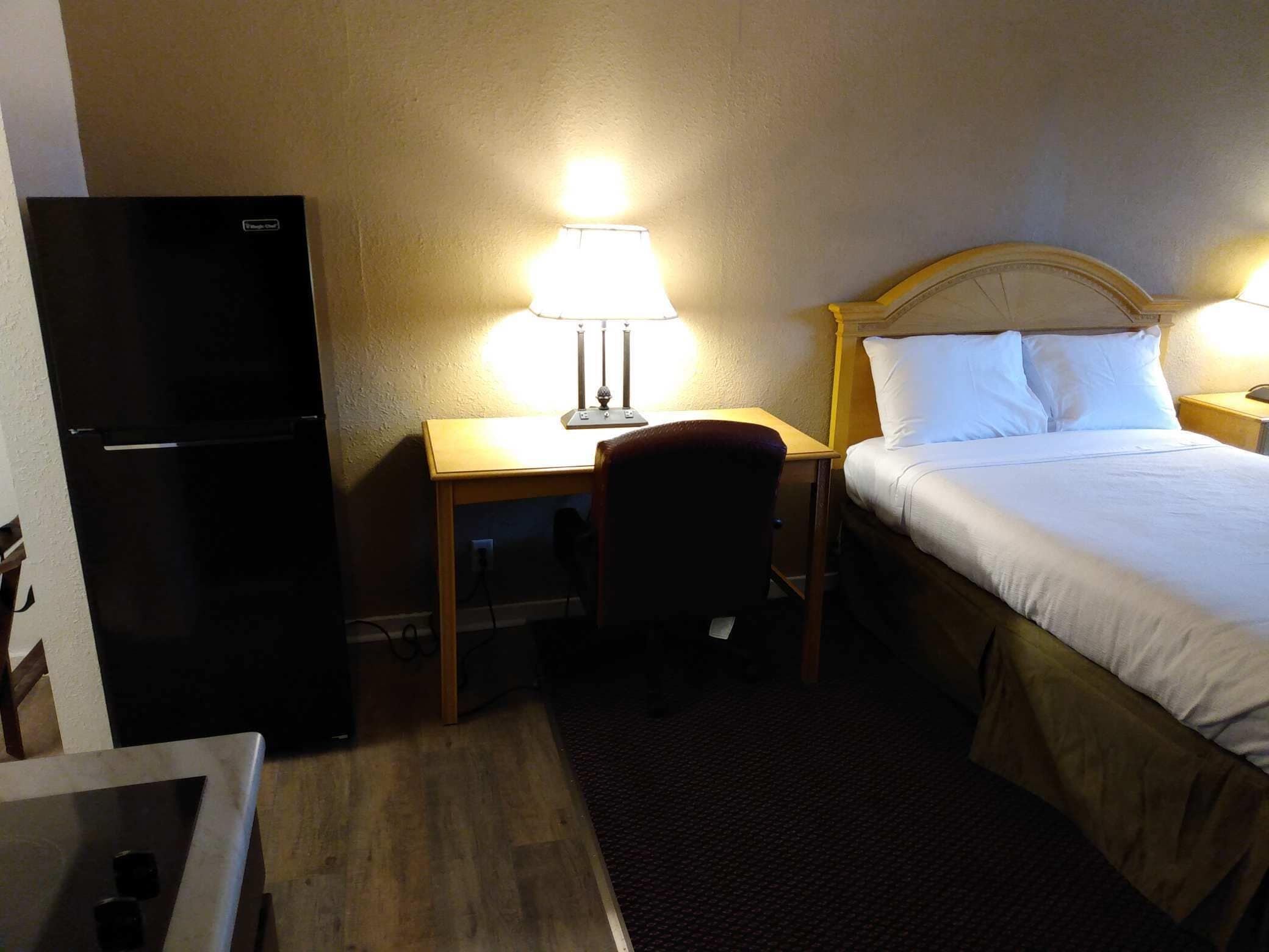 Ein Hotelzimmer mit Bett, Schreibtisch, Stuhl und Kühlschrank.