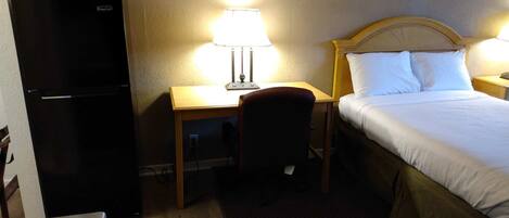 Ein Hotelzimmer mit Bett, Schreibtisch, Stuhl und Kühlschrank.
