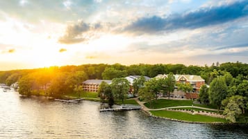 A riverside hotel with a dock, lush greenery, and a well-maintained lawn.