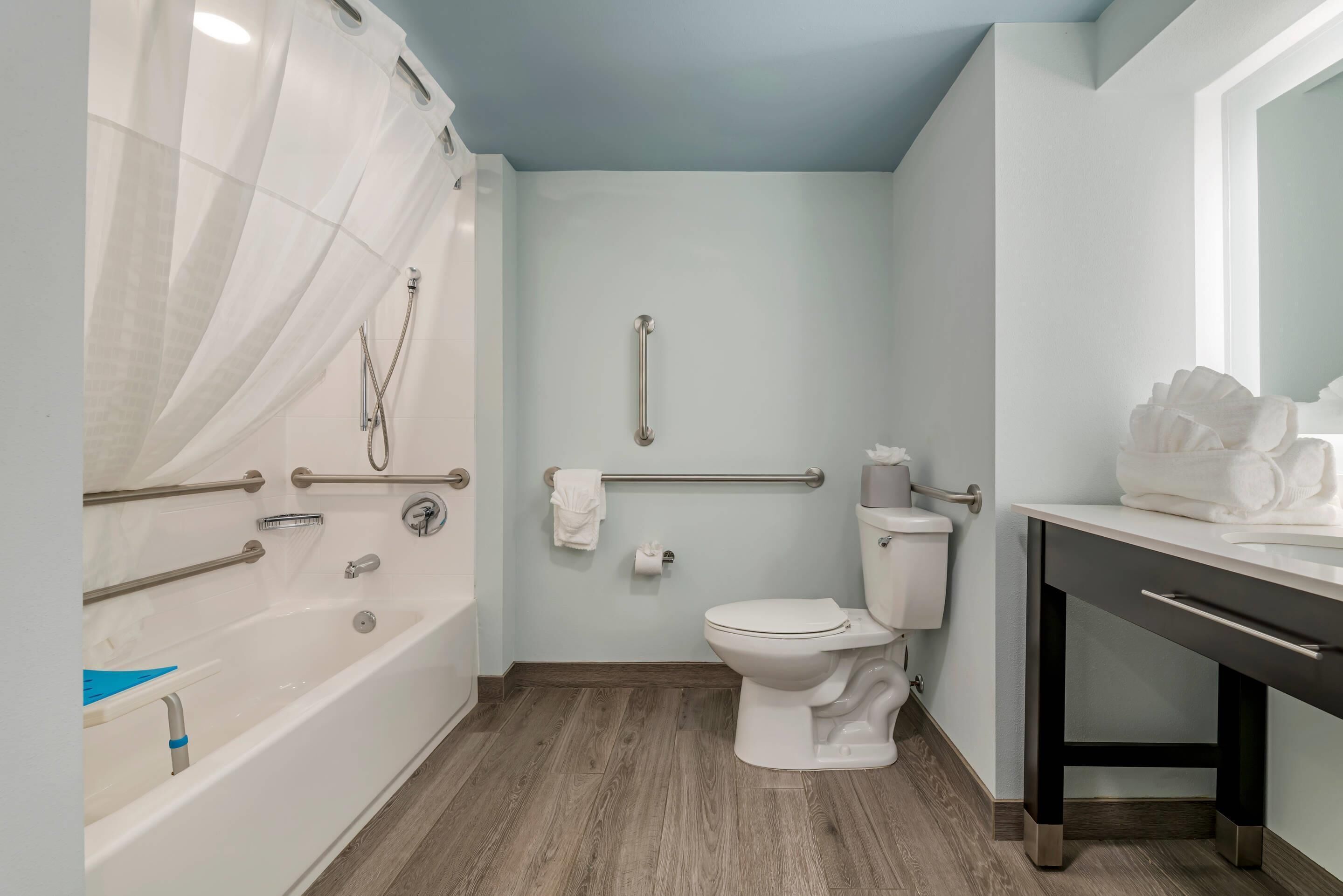 Un baño con bañera, inodoro y tocador con espejo.