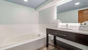 A modern bathroom with a bathtub, a vanity with a mirror, and a wooden door.