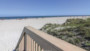 Een strand met een houten looppad dat naar het strand leidt.