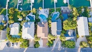 An aerial view of a coastal property with multiple swimming pools, a marina, and lush greenery.