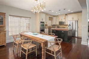 Una cocina moderna con armarios de madera, una isla central y un comedor con mesa y sillas de madera.