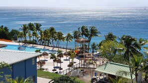 Un complexe hôtelier doté d’une piscine, de palmiers et offrant une vue sur l’océan.
