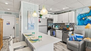 Una cocina moderna con armarios blancos, una isla central e iluminación colgante.