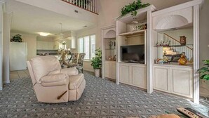 A spacious living room with a reclining chair, a flat-screen TV, and a built-in entertainment unit.