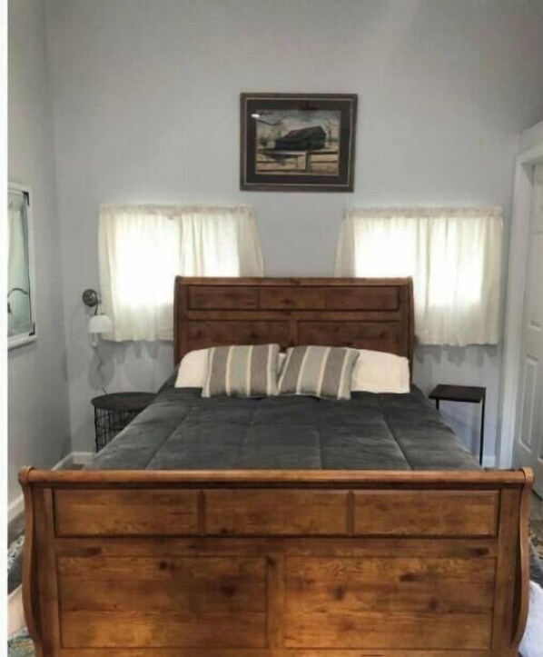 A wooden bed with a headboard, two bedside tables, and a framed picture on the wall. - Downtown Yellowstone Bungalow (Livingston)