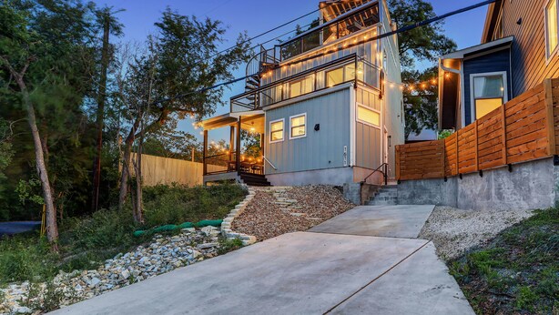 A modern two-story house with a concrete pathway leading to the entrance.