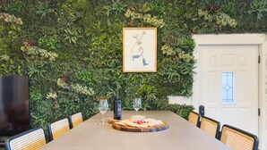 A dining table with a green wall backdrop, framed artwork, and a wine bottle.