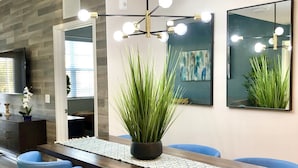 Un comedor moderno con una larga mesa de madera, sillas azules y una planta en maceta.
