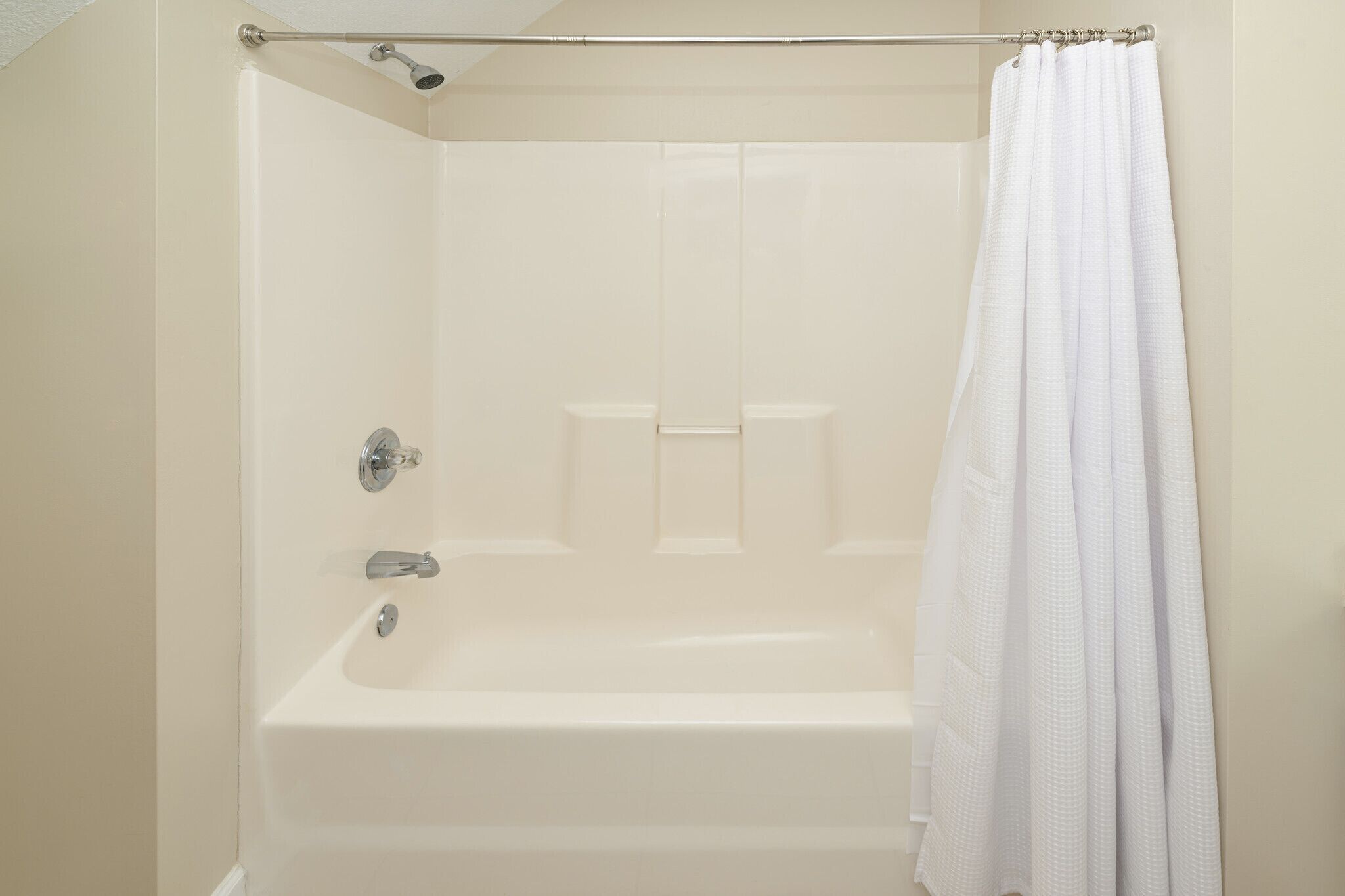 Une douche avec un rideau, une baignoire et un pommeau de douche.