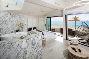 A modern bathroom with a marble vanity, a large bathtub, and a view of the sea through a glass door. - Beachfront Luxury Suite w/ Ocean Views & Balcony - Unit 224 at Terrasol (Cabo San Lucas)