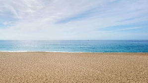 A beach with a wide sandy shore and calm blue sea under a clear sky.