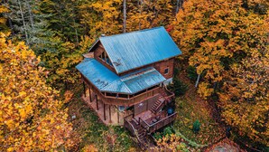 A wooden cabin with a blue roof surrounded by autumn foliage.