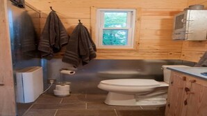 A compact bathroom with a toilet, a window, and wooden walls. - Masons Chapel at Springfield 1842 (Halifax)
