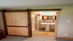 Ein Badezimmer mit Holztür, Waschbecken und Spiegel.