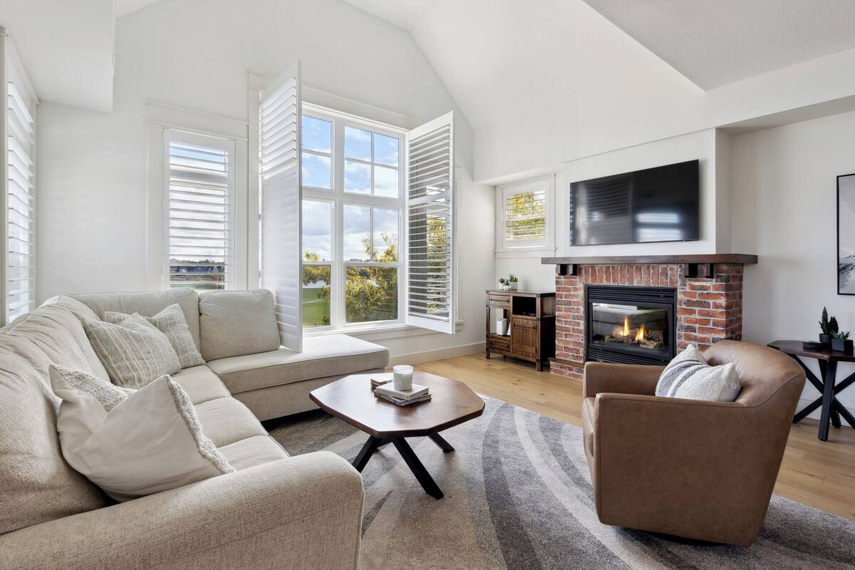 A modern living room with a fireplace, a sofa, a coffee table, and a TV mounted on the wall.