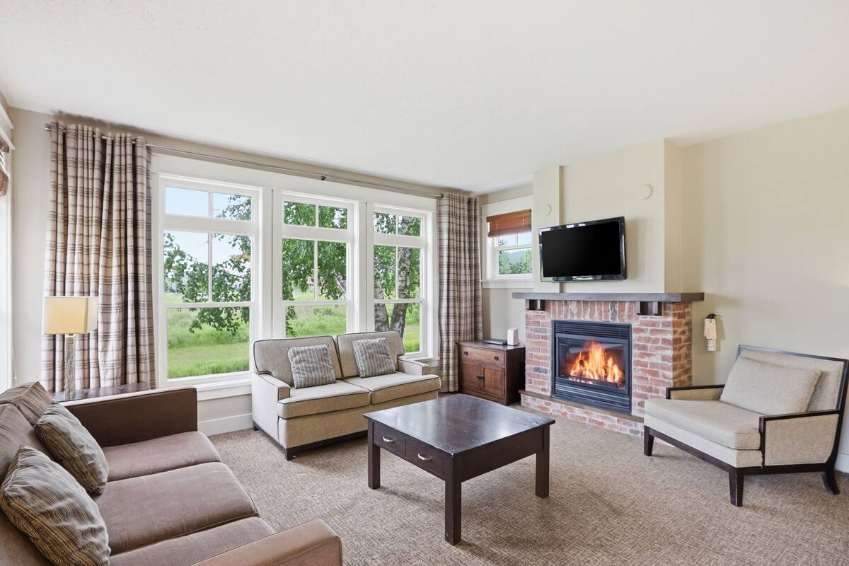A living room with a fireplace, sofa, armchair, and a television.