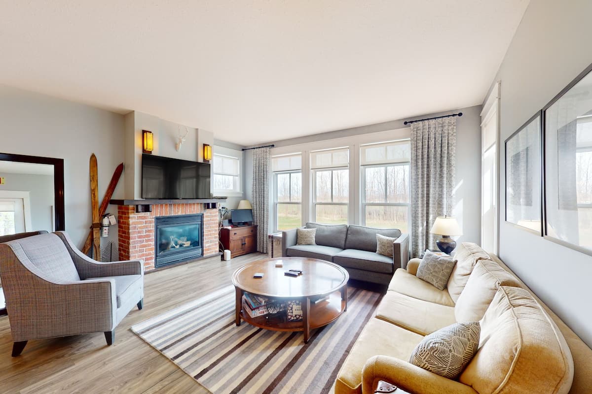 A modern living room with a fireplace, a sofa, a coffee table, and a television.