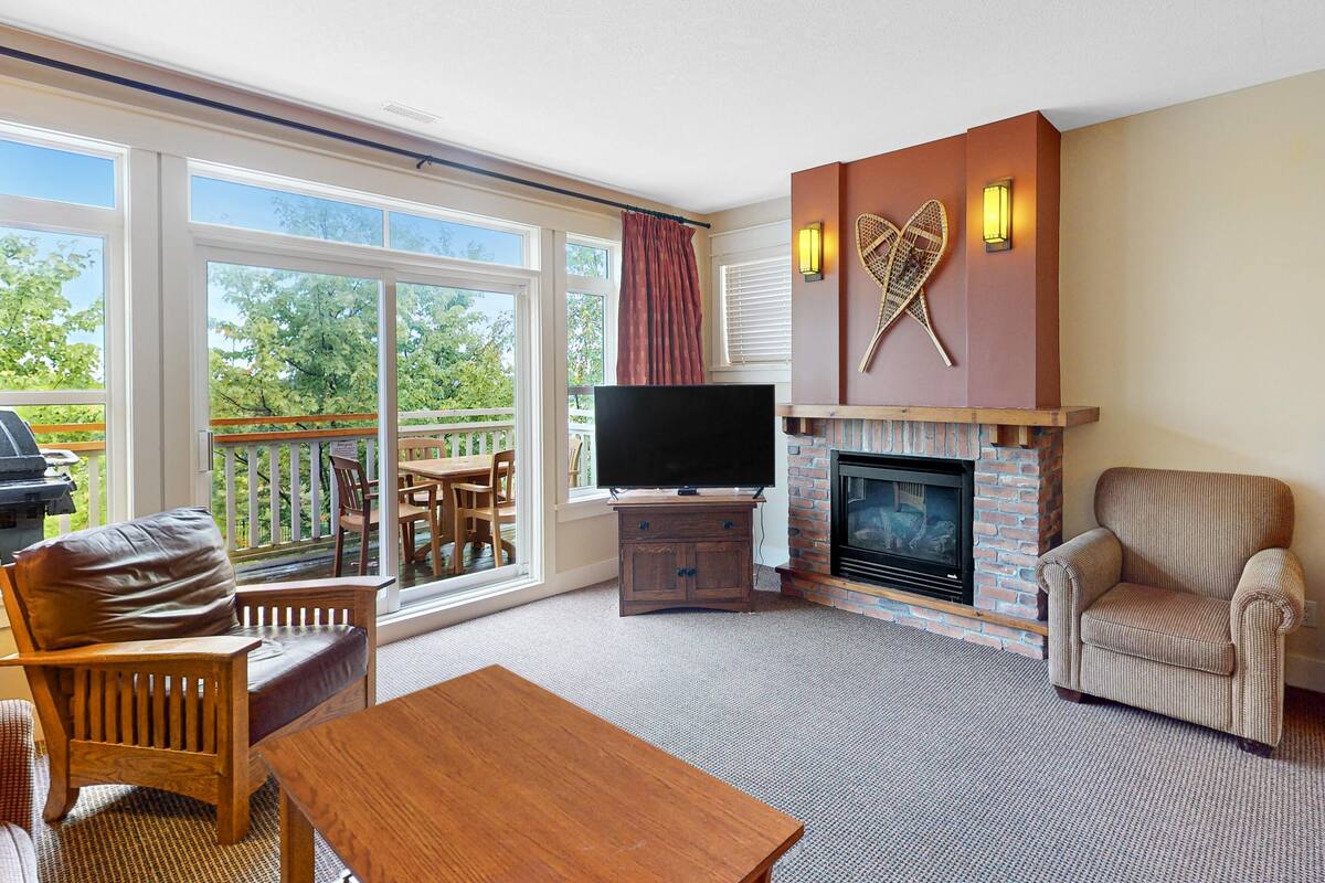 A living room with a fireplace, television, and outdoor patio.