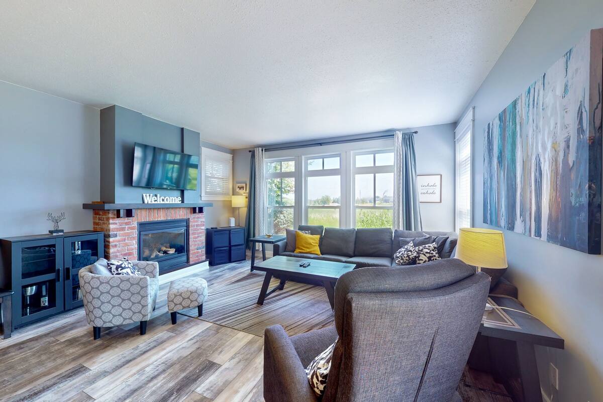 A modern living room with a fireplace, a television, and a large window with curtains.