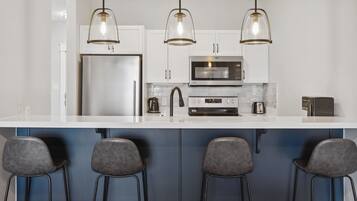 A modern kitchen with a large island, stainless steel appliances, and bar stools.