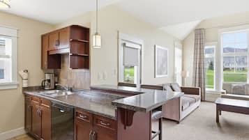 A kitchen with granite countertops, a dishwasher, and a large island. There is a dining area with a sofa and a coffee table.