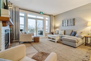 Una sala de estar moderna con chimenea, un conjunto de sofás y un ventanal que ofrece vistas al exterior.