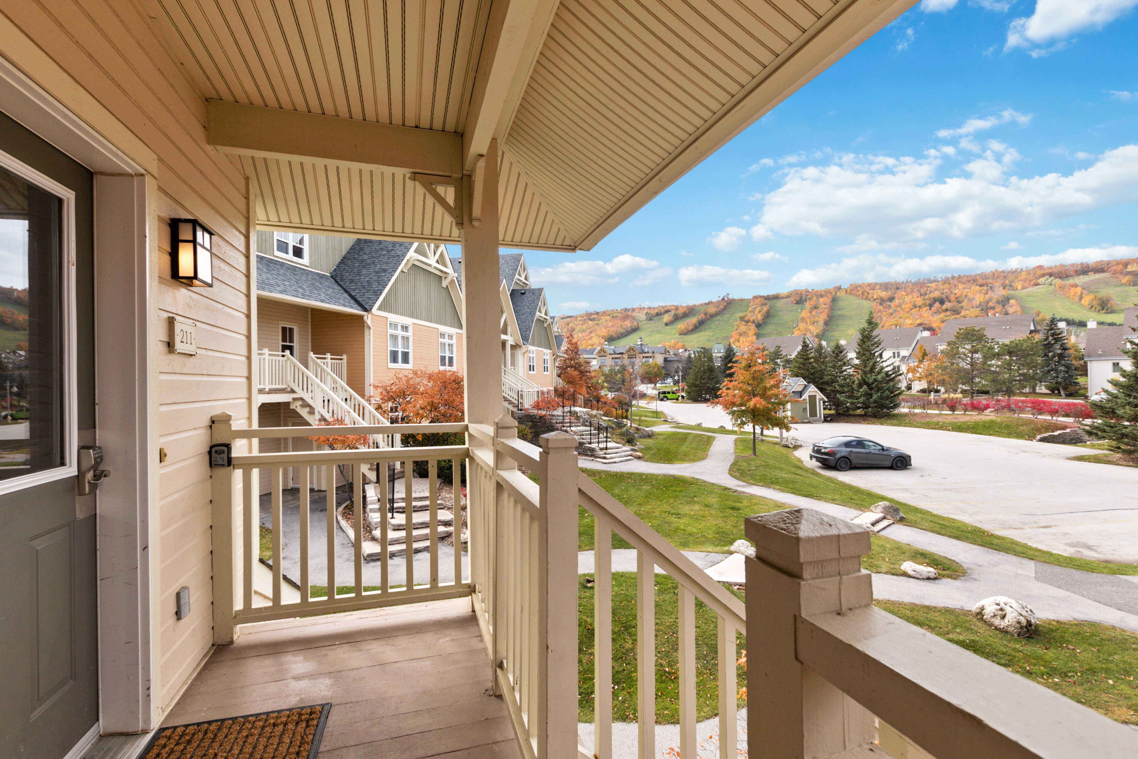 A porch with a view of a residential street and autumn foliage.