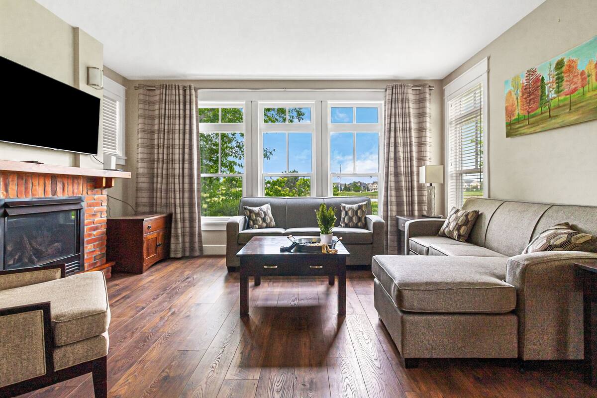A living room with a fireplace, two sofas, a coffee table, and a TV.