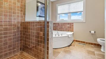 A bathroom with a glass shower enclosure, a bathtub, and a toilet.