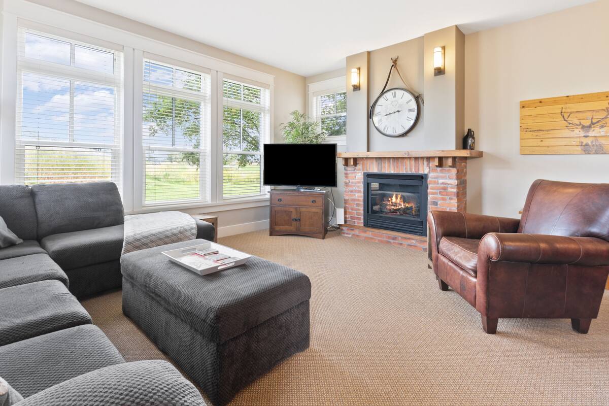 A living room with a fireplace, a leather armchair, a gray sofa, and a television.
