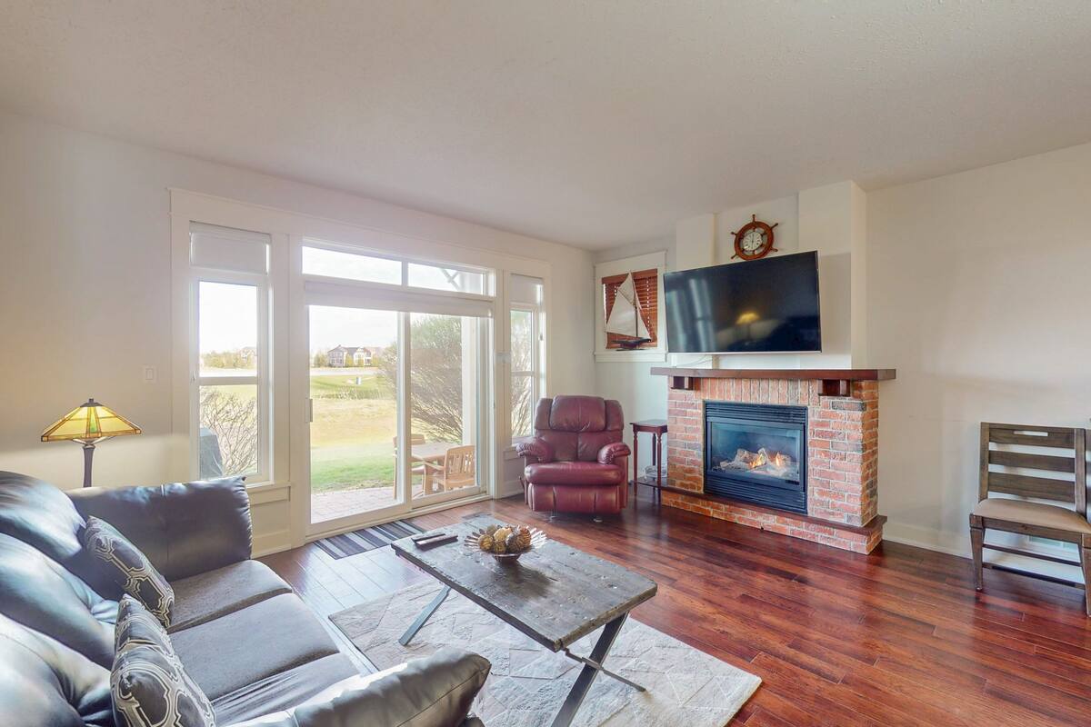 A living room with a fireplace, leather sofa, and a television.