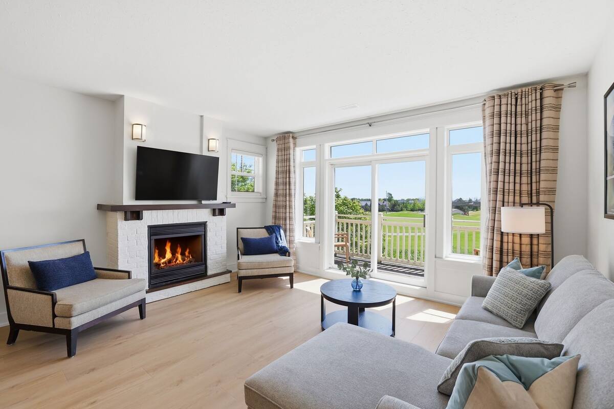 A living room with a fireplace, sofa, armchair, and a television.