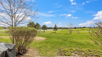 A golf course with a clear sky, a paved walkway, and a covered seating area.