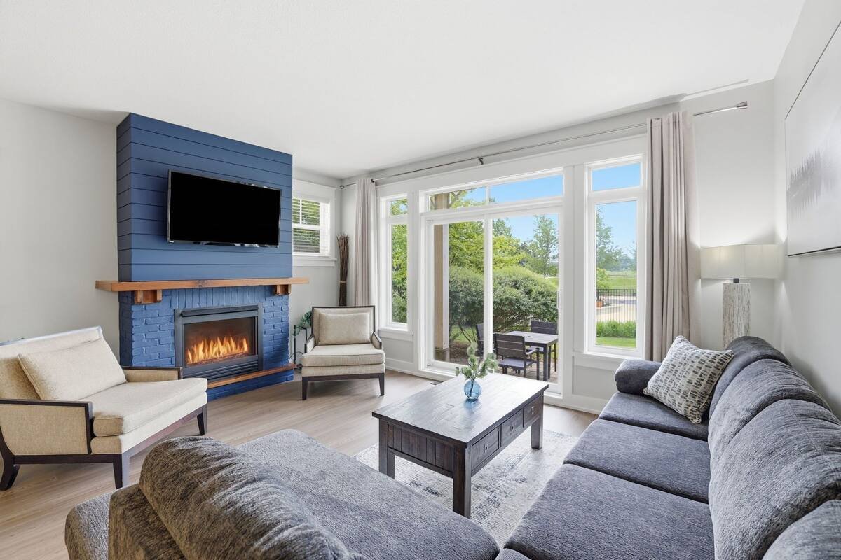 A living room with a fireplace, a sofa, a coffee table, and a TV mounted on a blue wall.