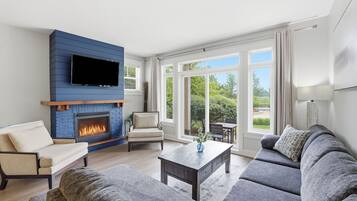 Una sala de estar con chimenea, un sofá, una mesa de centro y un televisor montado en una pared azul.