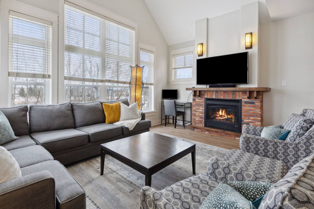 A spacious living room with a large sectional sofa, a coffee table, and a fireplace.