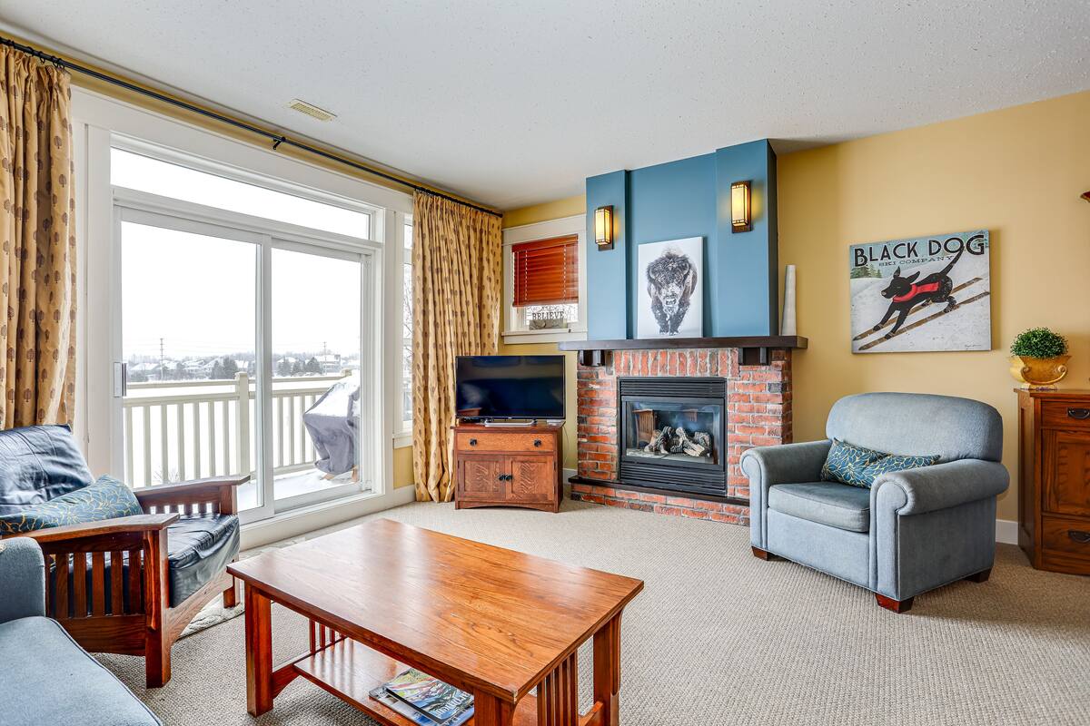 A living room with a fireplace, a television, and a large window with curtains.