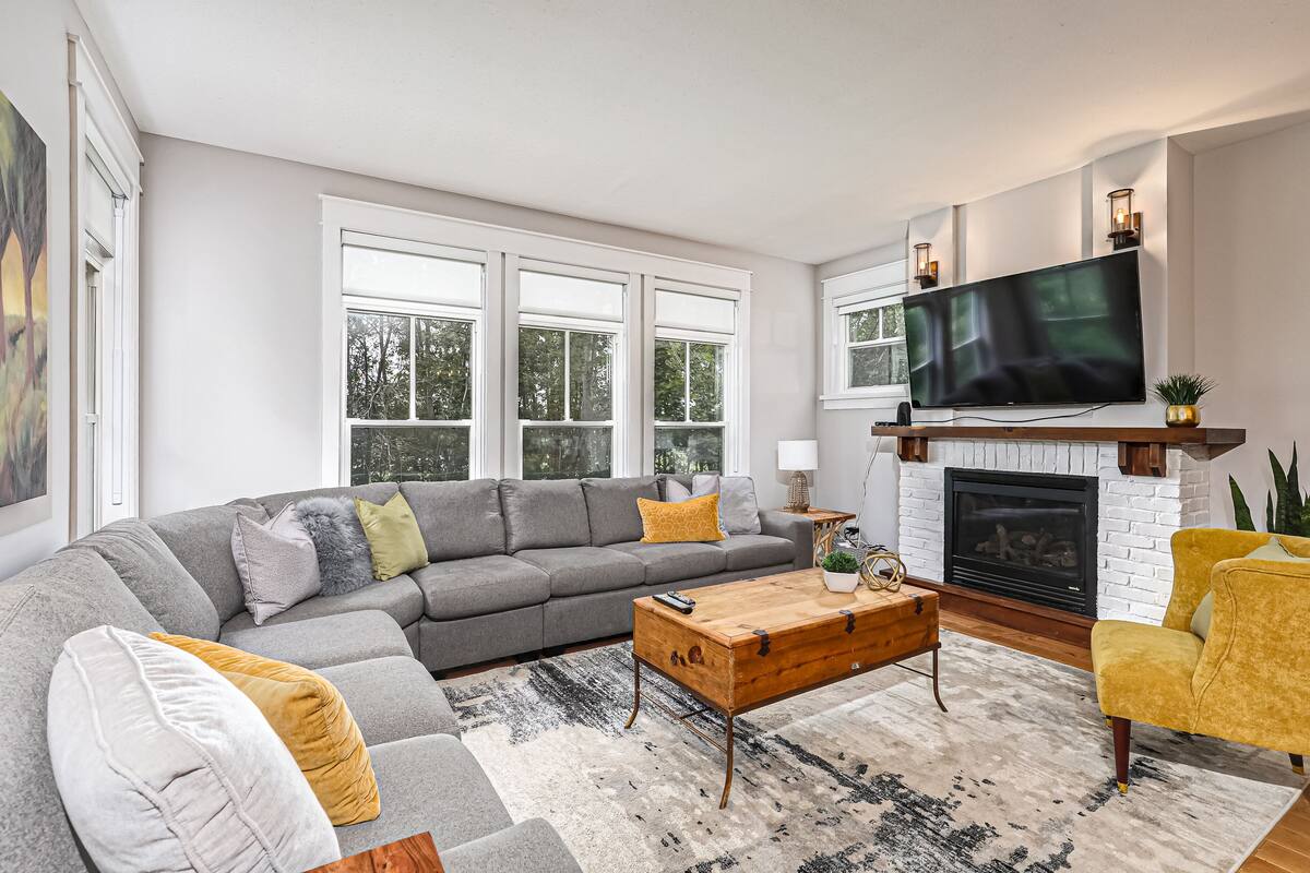 A modern living room with a sectional sofa, a wooden coffee table, a fireplace, and a large flat-screen TV.