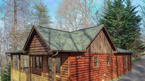 A wooden cabin with a porch and a covered deck, surrounded by trees. - Couples Getaway! Private, Romantic, Cabin with Jacuzzi & Hot Tub in Gatlinburg (Gatlinburg)