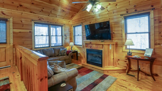 A cozy cabin interior with a wooden ceiling, a fireplace, a television, and a sofa. - Couples Getaway! Private, Romantic, Cabin with Jacuzzi & Hot Tub in Gatlinburg (Gatlinburg)