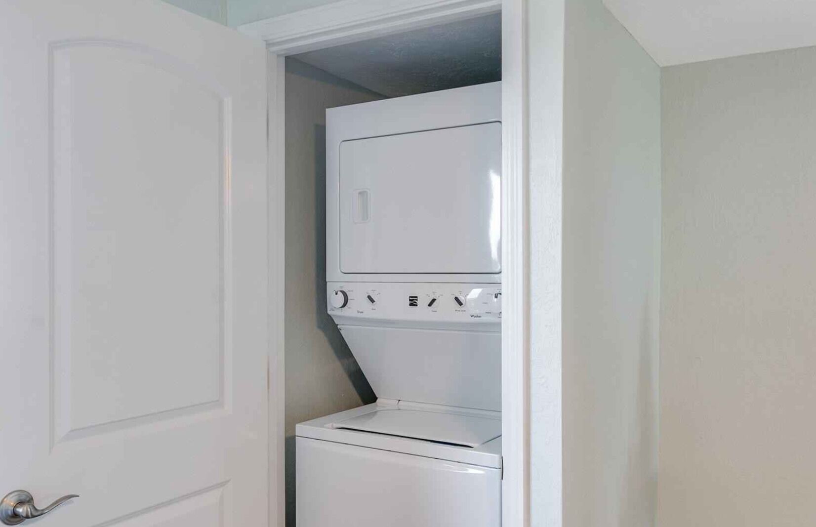 A laundry room with a front-loading washer and dryer stacked vertically.