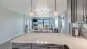 Cozinha moderna com uma ilha grande, luminárias pendentes e vista para o exterior.